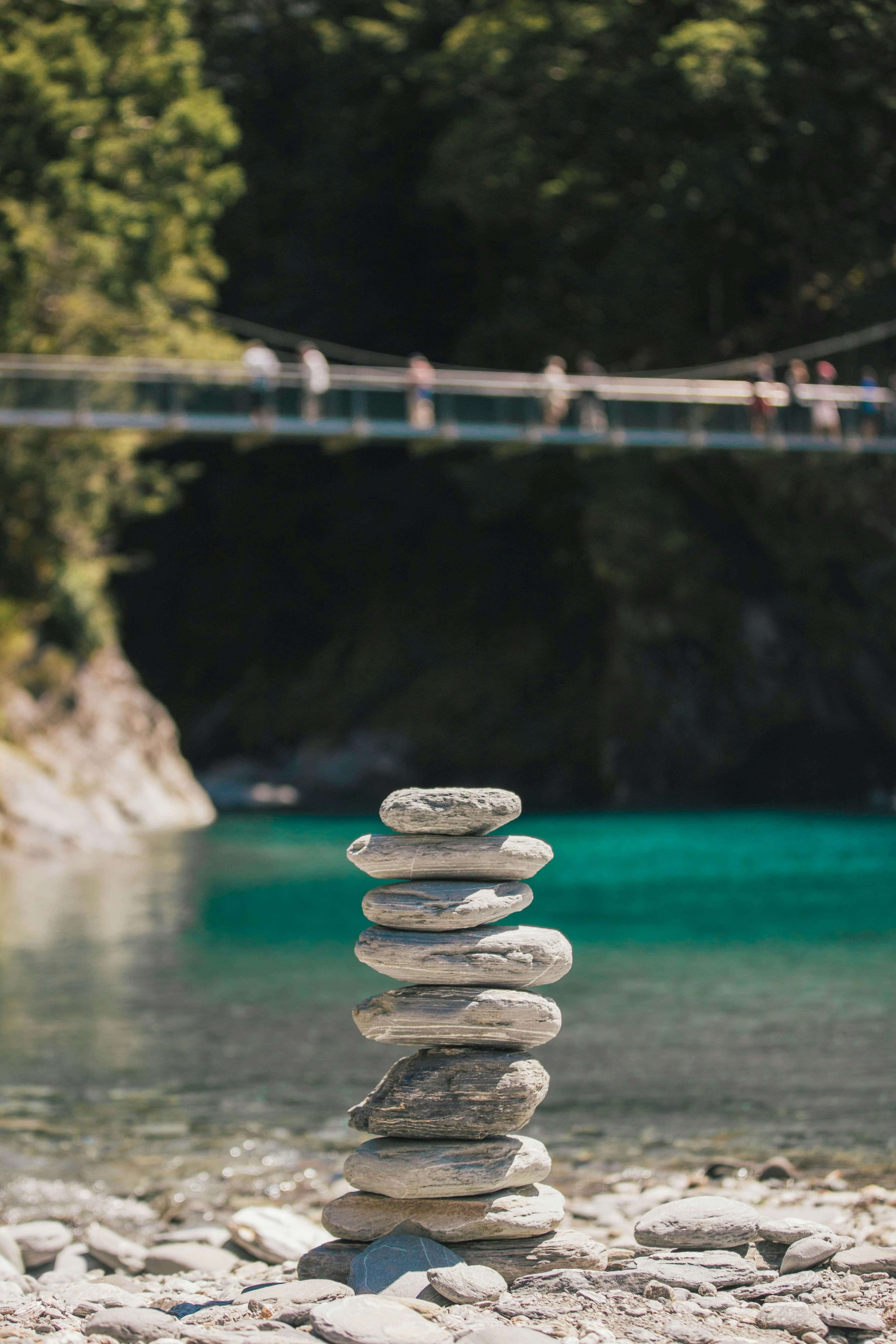 peaceful close-up of stones with water and a bridge in the background